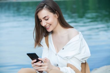 Kız dışarıda cep telefonuna mesaj atıyor. Telefonu olan kız. Telefonunda mutlu bir kadın metin sms mesajı Portresi.