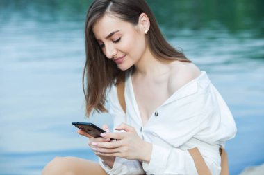 Kız dışarıda cep telefonuna mesaj atıyor. Telefonu olan kız. Telefonunda mutlu bir kadın metin sms mesajı Portresi.