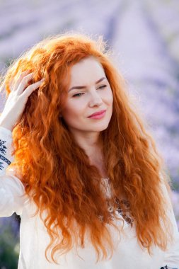 Uzun kıvırcık kızıl saçlı güzel bir kızın yaz portresi. Uzun saçlı kadın. Lavander alanında Avrupalı kız.