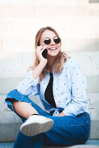 Young girl reading a book in the street.  female hipster enjoying literature outdoors. Smiling teen girl dressed in casual reading book.