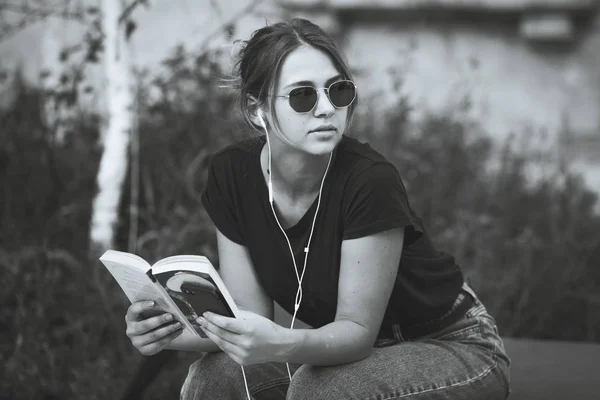 通りで本を読んでいる若い女の子 屋外で文学を楽しむ女性ヒップスター カジュアルな読書本に身を包んだ笑顔の十代の少女 — ストック写真