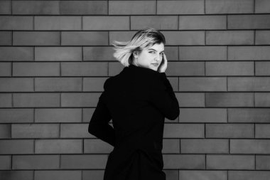 Dalgalı saçlı Avrupalı tatlı kız şehirde şakacı poz veriyor. Güzel kadın sağlıklı ten konsepti doğal makyaj güzel kız yüzü. Şehir caddesinde güzel, şık bir kadının resmi.