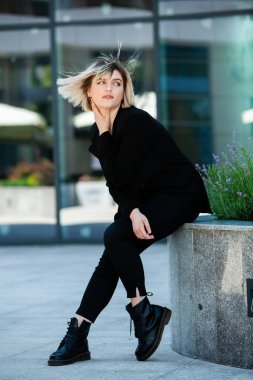 Dalgalı saçlı Avrupalı tatlı kız şehirde şakacı poz veriyor. Güzel kadın sağlıklı ten konsepti doğal makyaj güzel kız yüzü. Şehir caddesinde güzel, şık bir kadının resmi.