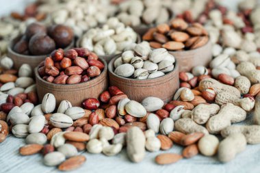 Geçmişi için çeşitli fındıklar. Badem, ceviz, ceviz, fıstık, fındık, fıstık, Macadamia. Çeşit çeşit fındık koleksiyonu. Kurumuş meyveli kompozisyon. Sağlıklı yiyecekler. Organik.