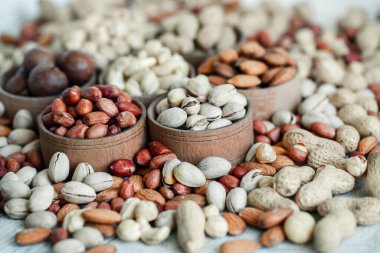 Geçmişi için çeşitli fındıklar. Badem, ceviz, ceviz, fıstık, fındık, fıstık, Macadamia. Çeşit çeşit fındık koleksiyonu. Kurumuş meyveli kompozisyon. Sağlıklı yiyecekler. Organik.