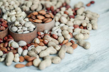 Geçmişi için çeşitli fındıklar. Badem, ceviz, ceviz, fıstık, fındık, fıstık, Macadamia. Çeşit çeşit fındık koleksiyonu. Kurumuş meyveli kompozisyon. Sağlıklı yiyecekler. Organik.