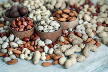 Geçmişi için çeşitli fındıklar. Badem, ceviz, ceviz, fıstık, fındık, fıstık, Macadamia. Çeşit çeşit fındık koleksiyonu. Kurumuş meyveli kompozisyon. Sağlıklı yiyecekler. Organik.