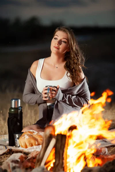 아름다운 아가씨가 불타는 마시고 냉소주의자들의 자연의 낭만적 분위기 캠프파이어 — 스톡 사진