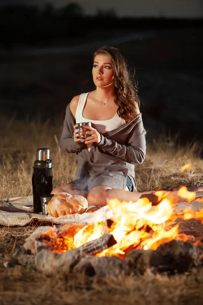 아름다운 아가씨가 불타는 마시고 냉소주의자들의 자연의 낭만적 분위기 캠프파이어 — 스톡 사진