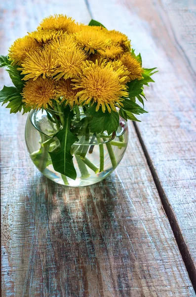 Bouquet di denti di leone in un vaso di vetro su un vecchio sfondo di legno — Foto Stock