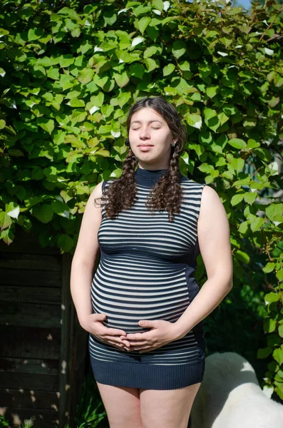 Fotografie Těhotné Ženy Pozadí Zelených Listů Pruhovaných Šatech Rukama Břiše — Stock fotografie