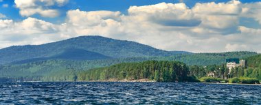 Güzel dağ gölü, bulutlu mavi gökyüzü. Urallar 'da Turgoyak Gölü baharı.