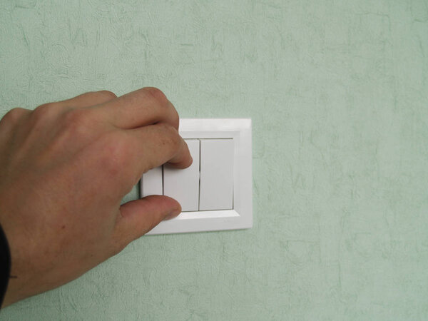 hand turns off the light on the switch located on the wall