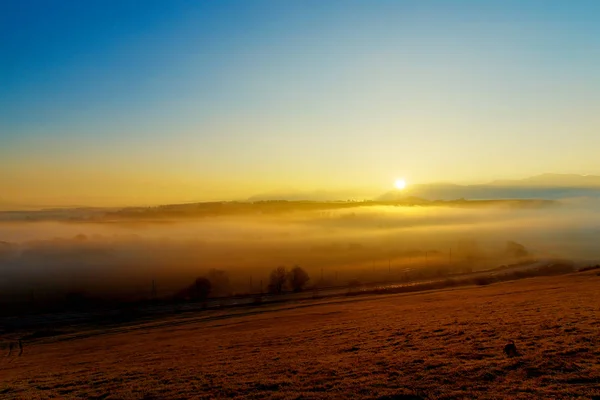 Прекрасный утренний пейзаж в тумане с дорогой и железной дорогой . — стоковое фото