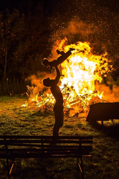 Vader die zijn zoontje vasthoudt met brandend kampvuur op achtergrond, vaderschap en levensvreugde. Licht grafisch effect. — Stockfoto