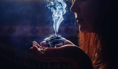 incense in a woman hand, incense smoke on a black background clipart