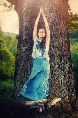 Genç kadın ağaçta yoga yapıyor..