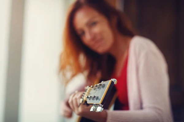 Kvinna spelar med gitarr och suddig bakgrund. — Stockfoto