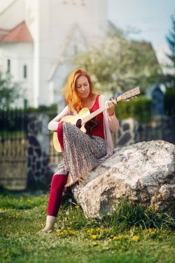 Gitarla oynayan ve arka planı bulanık bir kadın..