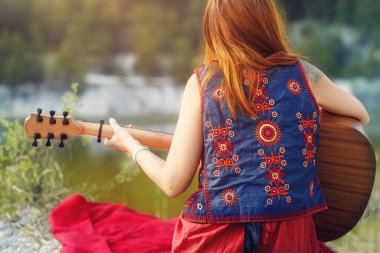 Gitarla oynayan ve arka planı bulanık bir kadın..