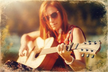 Doğada gitarla oynayan güzel bir kadın. Eski fotoğraf efekti.