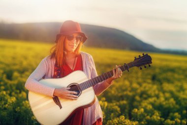 Gitarla oynayan ve arka planı bulanık bir kadın..