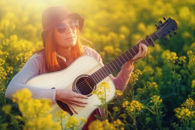 Gitarla oynayan ve arka planı bulanık bir kadın..