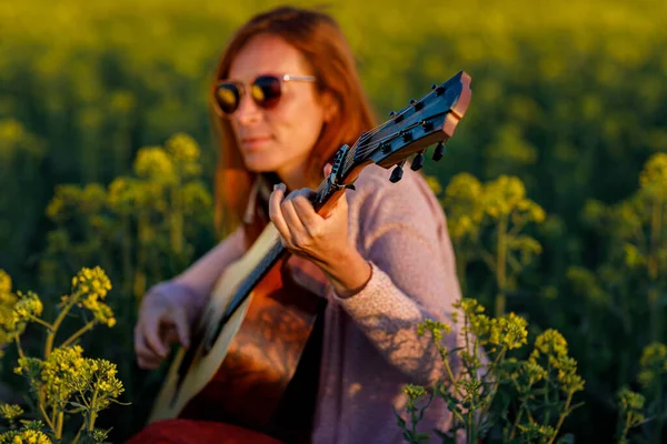 Donna che suona con chitarra e sfondo sfocato. — Foto Stock