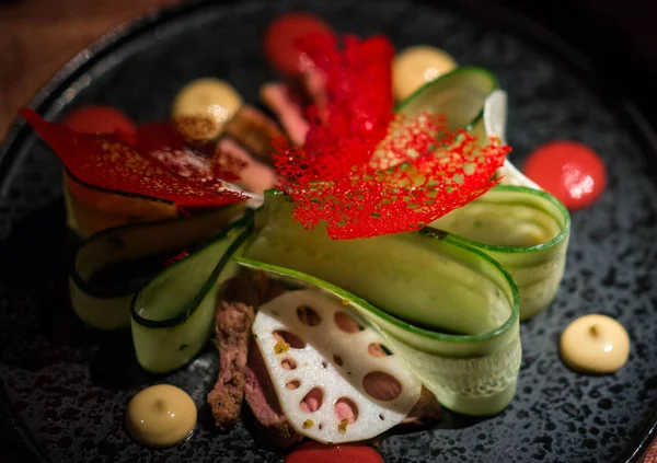 Beautifully decorated Peking duck salad with vegetables on a glass tray