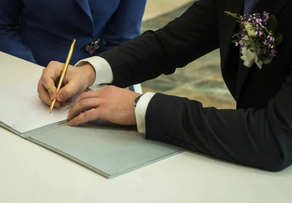 Händerna på brudgummen undertecknande äktenskapsförord och brudgummen boutonniere — Stockfoto