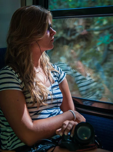 Chica joven en la iluminación del atardecer viajando en vagón de tren y su ref — Foto de Stock