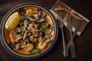 Deniz ürünleri salatası - karides, mürekkep balığı ve limonlu deniz kabuğu ve peçeteli çatal bıçak.