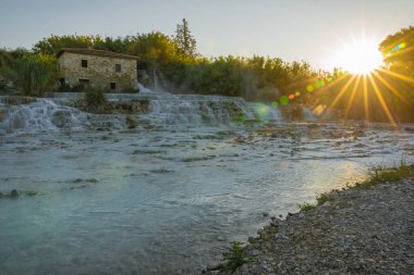 Güneşin yükselen ışınları İtalya 'nın Toskana kentindeki Satürn' de vahşi nehrin termal suları üzerinde.