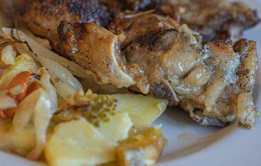 Beyaz tabakta patates ve sebzeli fırında domuz resmi, seçici odaklı.