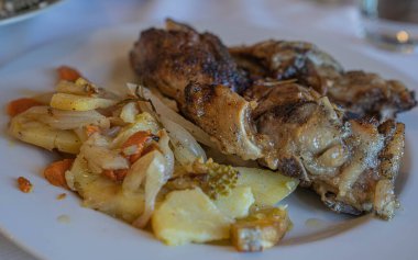 Beyaz tabakta patates ve sebzeli fırında domuz resmi, seçici odaklı.