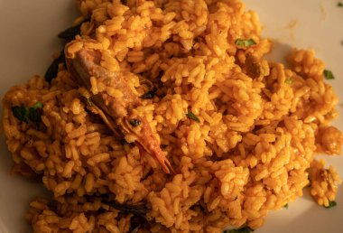 Beyaz tabakta deniz ürünleri ve karidesli kırmızı risotto resmi