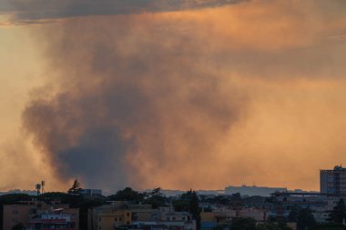 Roma, İtalya 'da gün batımının erken saatlerinde gökyüzünde çıkan bir yangının dumanı.
