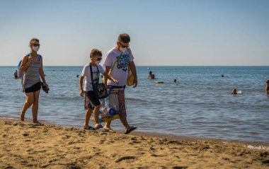 Bufalara, İtalya - 21 Ağustos 2020, İtalya 'da Bufalara plajında maske takan bir aile. Koronavirüs pandemisinin ikinci dalgasını bekliyor.