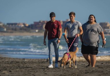 Marina di San Nicola, İtalya - 08 Ekim 2020, koruyucu maskeleri olmadan deniz kıyısında yürüyen üç genç adam. İtalya 'da sosyal uzaklık bozulması, koronavirüsün ikinci dalgası (covid 19)