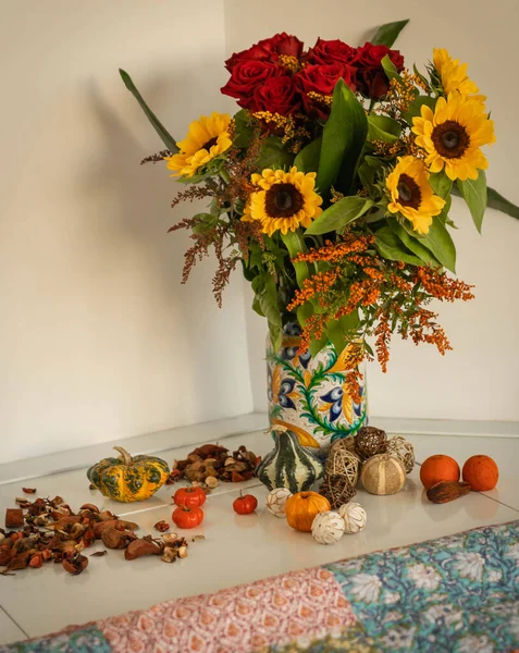 Autumn bouquet with sunflowers and roses and mini pumpkins around in Italy