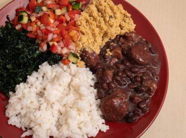 Beş malzemeden oluşan geleneksel Brezilya yemeği resmi - feijoada, farofa, İngiliz sosu, pirinç ve kırmızı tabakta sığır eti