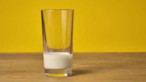 Hausgemachte Schokoladenkekse auf einem Holztisch neben einem Glas mit Milch gestapelt, gelber Hintergrund — Stockvideo