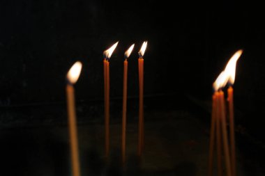 Siyah bir arka plan üzerinde mum alevleri. Kilisede dua mumları yakma.