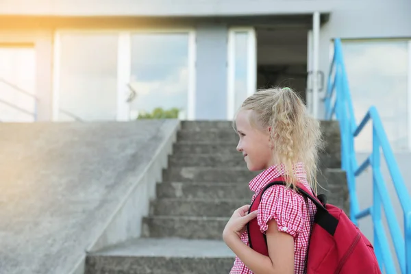 Back to school. Beautiful blond schoolgirl with red backpack outside the primary school. — Stock Photo, Image