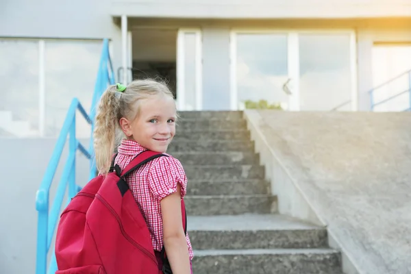 Back to school. Beautiful blond schoolgirl with red backpack outside the primary school., education concept. — Stock Photo, Image