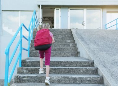 Okula geri dön. Kırmızı sırt çantası ile güzel sarışın kız öğrenci ilkokul dışında çalışan. 