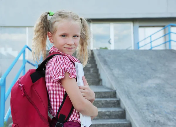Je retourne à l'école. Belle écolière blonde avec sac à dos rouge et livres en dehors de l'école primaire, concept d'éducation . — Photo