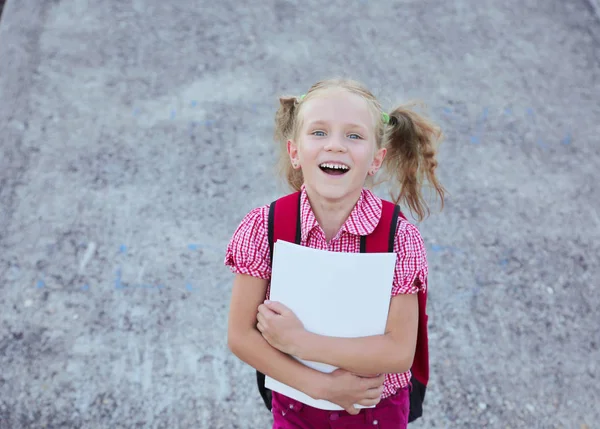 Back to school. Happy smiling beautiful blond schoolgirl with red backpack and books outside the primary school , education concept. — Stock Photo, Image