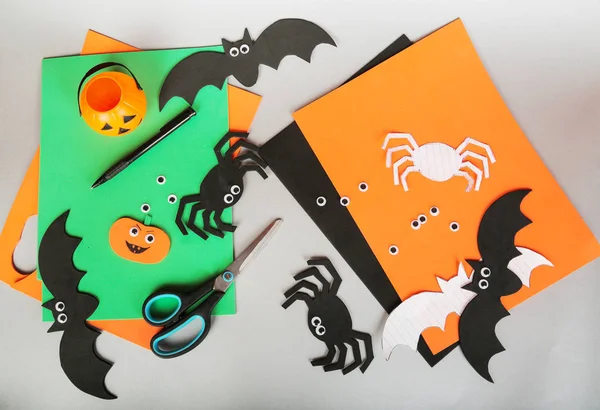 Paper felt Halloween hand made crafts. Felt pumpkin, spider, bat, eyes decorations on gray background. Scissors and materials. — Stock Photo, Image