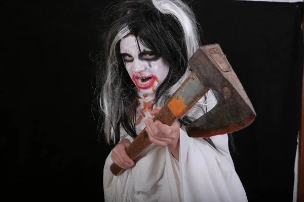 Halloweenská hororová představa. Roztomilá malá strašidelná holka z příšery zombie kostým s krví sekerou na černém pozadí. — Stock fotografie